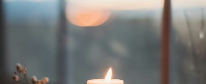 Lit candle in a window representing remembrance and holiday grief.